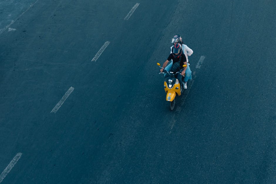 Two people riding a yellow motorbike on a city road in Istanbul, Turkey.
