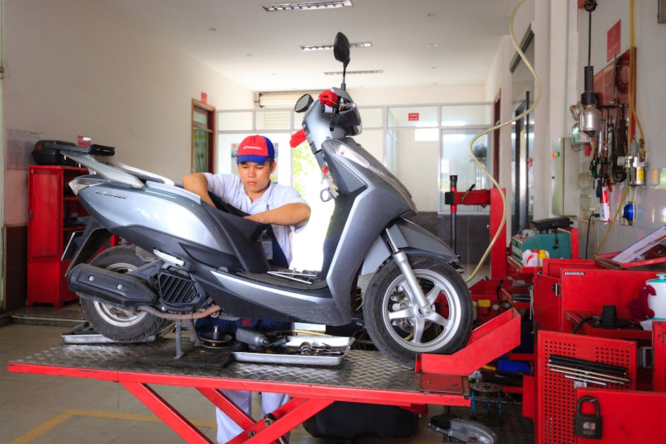 Mechanic working on a scooter in a well-equipped workshop, showcasing maintenance and repair services.