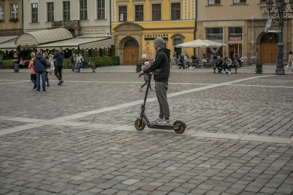 A man on an e-scooter rides through a bustling city square in Wrocław, Poland.