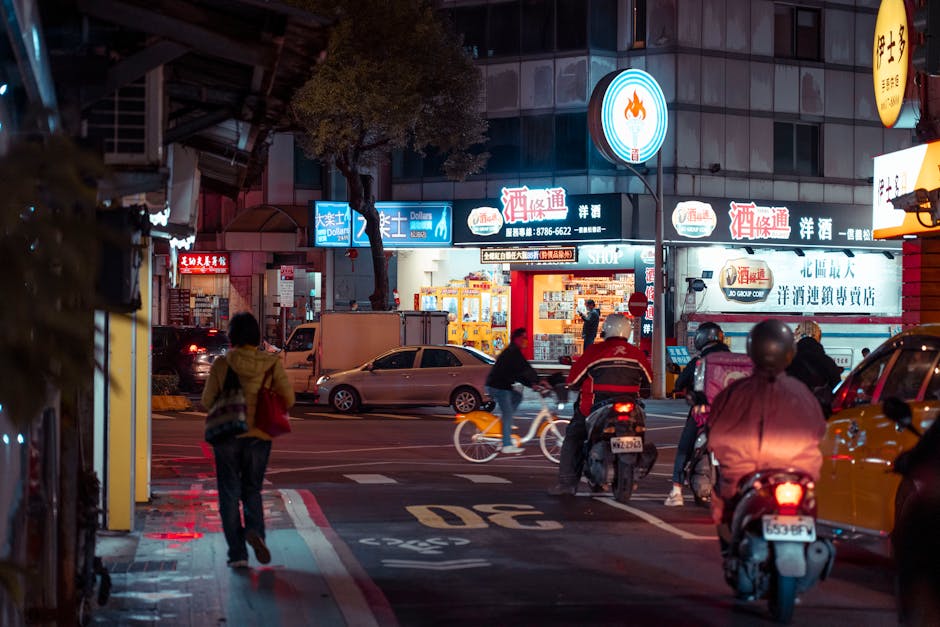 Busy night scene capturing city life, featuring pedestrians and cyclists under bright street lights.